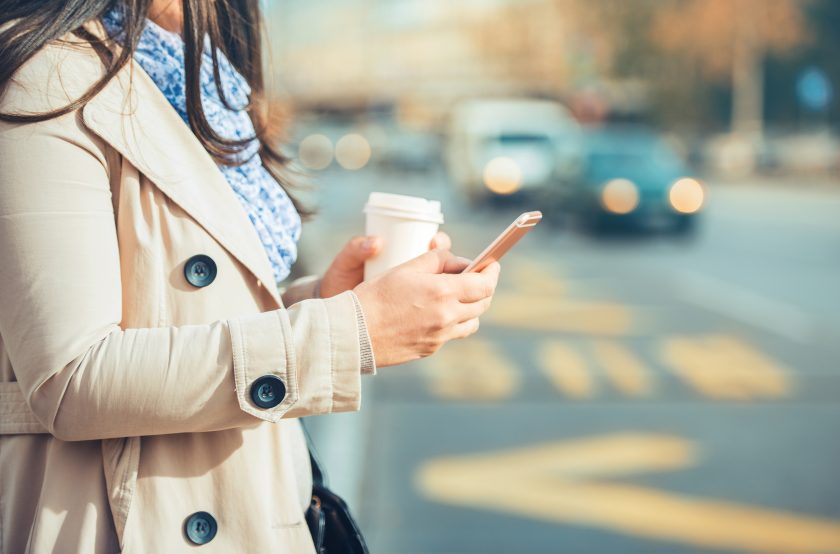 Femme avec cellulaire et café à la main