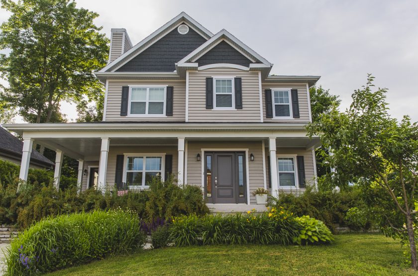 Grande maison beige unifamiliale entourée d'arbres