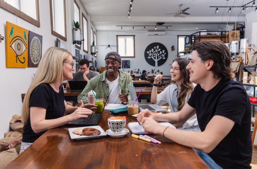 Des jeunes assis à une table dans un café qui discutent et rient.